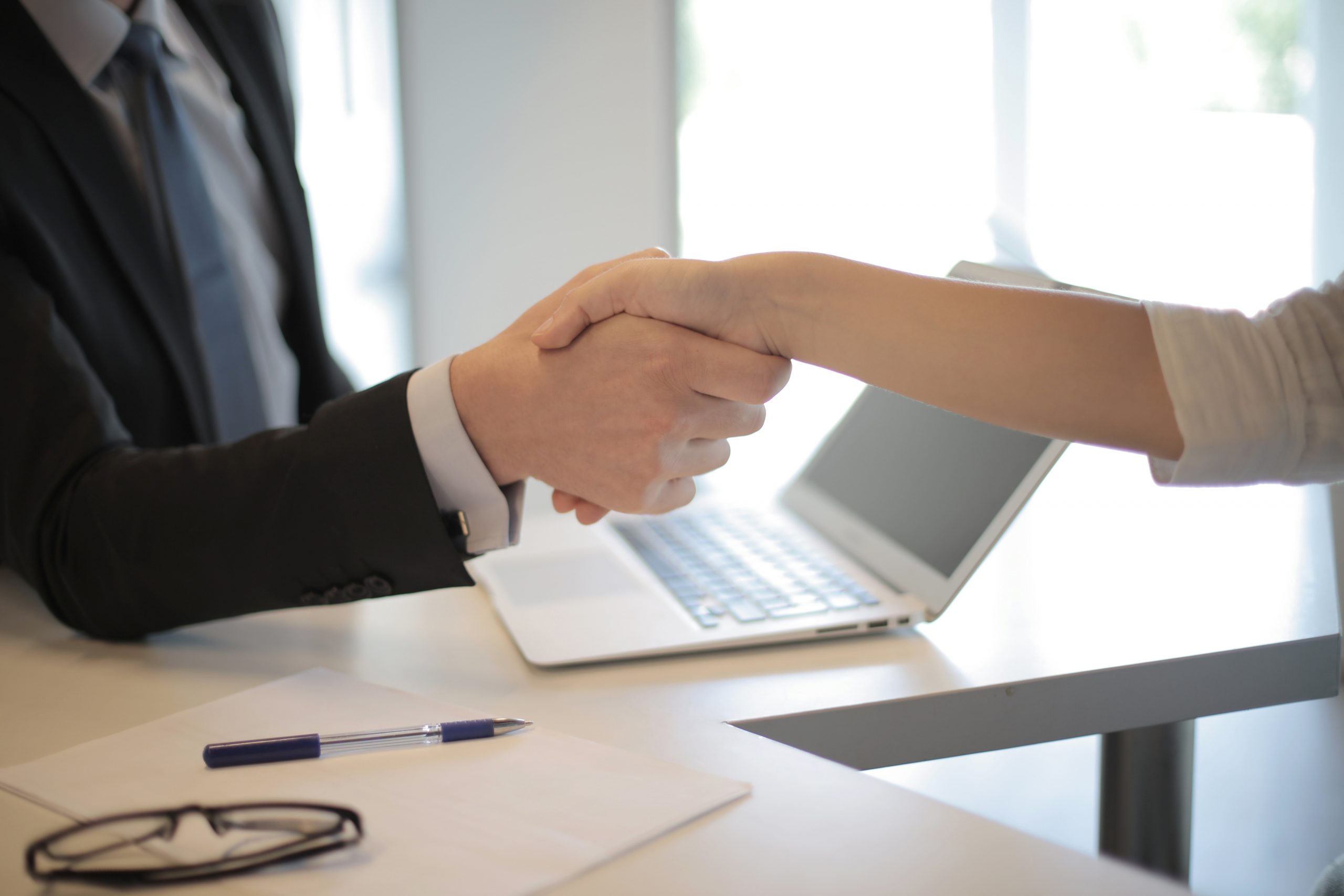 Handshake in Business Setting to Hire New Employee Suggesting Need for Employment Contract
